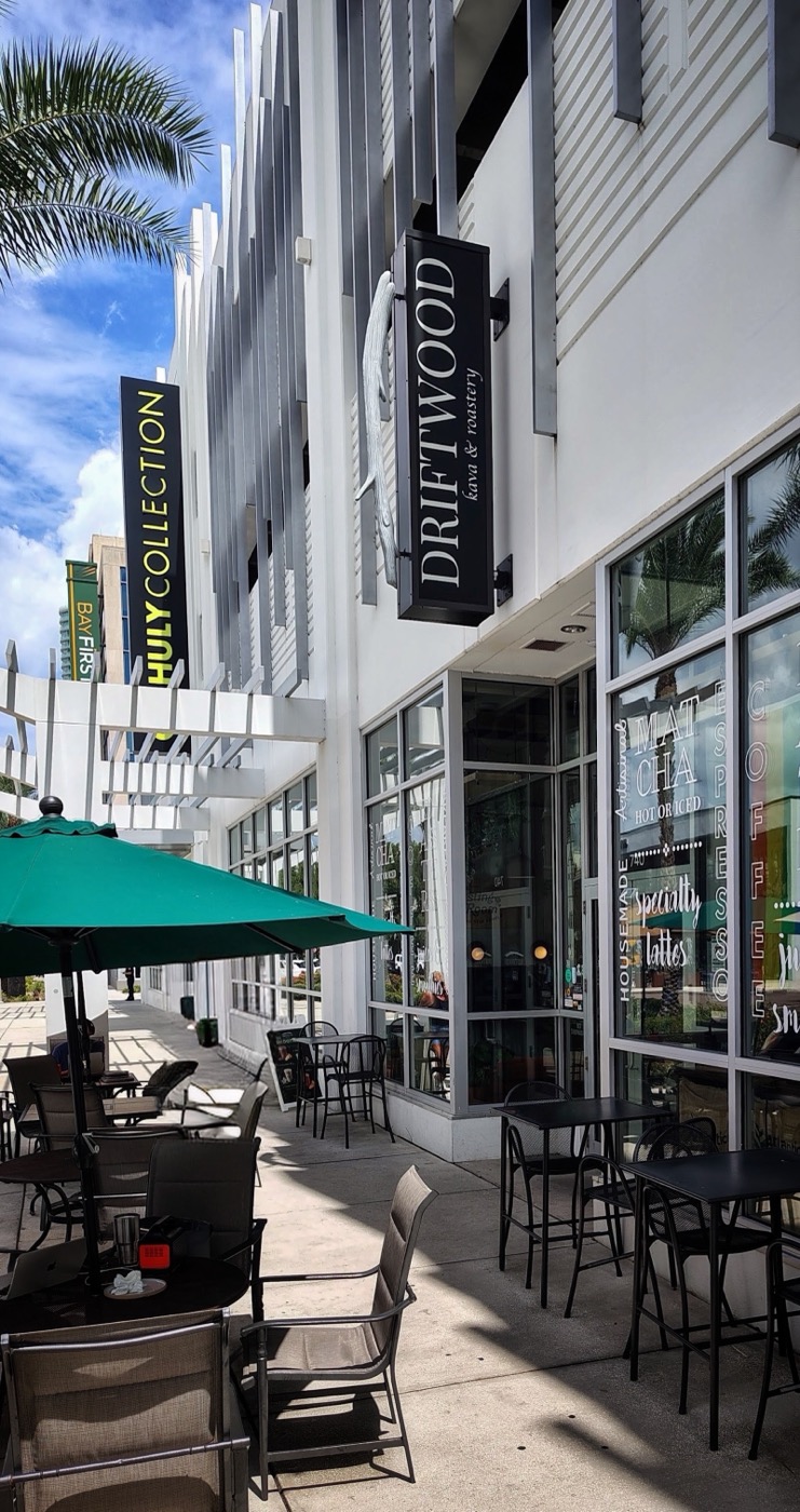 Driftwood’s storefront on Central Avenue, with its hanging sign and sidewalk patio under green umbrellas.